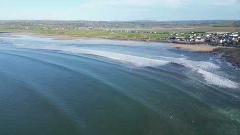 Aerial-tracking-shot-of-a-surfer-catching-a-wave-and-standing-up-at-Lahinch-Beach
