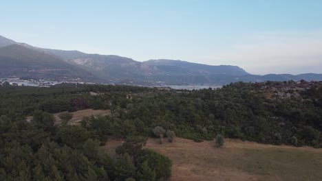 Retreating-drone-shot-of-above-the-woodlands-of-Sillyon,-revealing-the-town-below-and-showing-the-mountains-from-afar,-situated-in-Antalya-province-in-Turkey