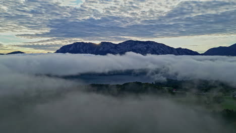 Vista-Aérea-De-La-Niebla-Moviéndose-Sobre-La-Naturaleza-Verde-En-Austria-Durante-La-Puesta-De-Sol