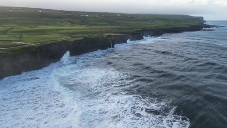 Aerial-dolly-shot-towards-a-small-waterfall-on-the-Doolin-cliffs,-Ireland
