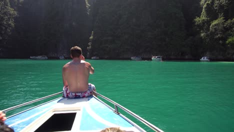 Young-Male-on-Bow-of-Boat-Enjoying-in-View-of-Majestic-Tropical-Lagoon-on-Thailand-Island