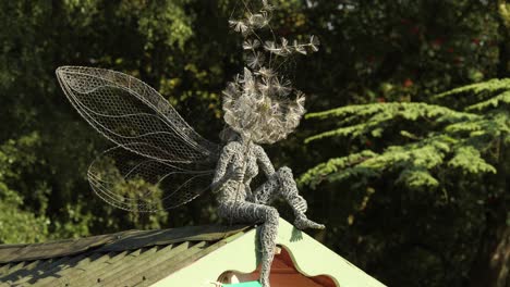 Wire-Fairy-Sitting-On-The-Rooftop-Blowing-A-Dandelion-In-Trentham-Estate-Gardens