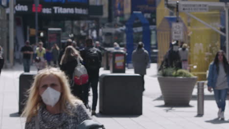 Two-women-walking-wearing-face-mask-in-Time-Square-with-crowd