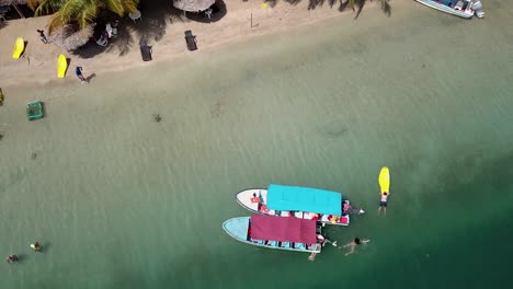 Vista-Aérea-De-La-Playa-De-Bocas-Del-Toro-Con-Barcos-Y-Gente-Nadando.