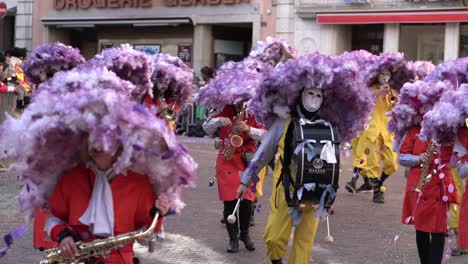 Solothurn,-Schweiz---03.-März-2019:-Ein-Musikalischer-Karnevalsclub-Mit-Riesigen-Violetten-Hüten,-Die-Wie-Blumen-Aussehen,-Die-Musikinstrumente-Wie-Trommeln-Und-Blechbläser-Spielen,-Während-Sie-Den-Karnevalsverkauf-Abwickeln