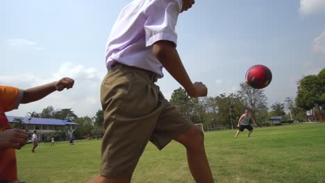 Action-Slowmotion-of-Thai-Kids-Playing-Football-on-Green-Grass-Field