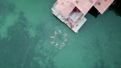 Aerial-ascending-shot-of-a-group-of-friends-doing-shapes-in-the-water
