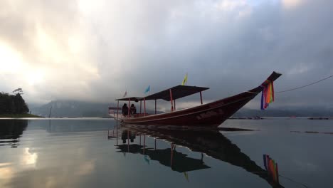 Traditionelles-Thailändisches-Longtail-Boot-Vor-Anker-Im-Ruhigen-Lagunenwasser-Mit-Spiegelreflexion-Am-Himmel
