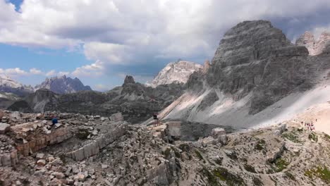 Aerial-Shot-of-Couple-Standing-on-Mountain-Ridge-in-the-Italian-Dolomites