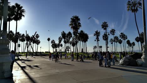 Masked-People-walking-on-the-world-famous-boardwalk-and-beach-on-a-sunny-afternoon,-in-Venice,-Los-Angeles,-California,-USA---still-view