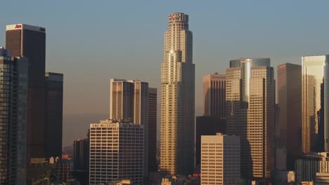 Aerial-view-of-sunlit-skyscrapers-in-Downtown,-Los-Angeles,-California,-USA,-during-sunset---Descending,-drone-shot