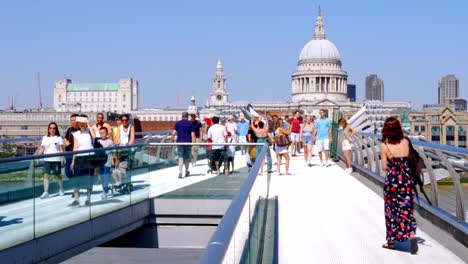 Pre-Pandemic,-normal-life-in-London,-locals-and-tourists-visiting-Millennium-Bridge---static-shot-looking-at-St-Pauls-Cathedral-with-pedestrians-crossing-Wobbly-bridge,-Great-Britain-UK-summer-time