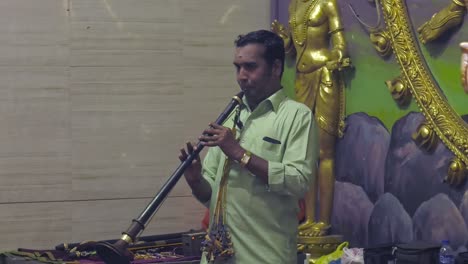 Man-Playing-Flute-During-Hindu-Ceremony-in-Sri-Veeramakaliamman-Temple,-Singapore---Medium-static-shot