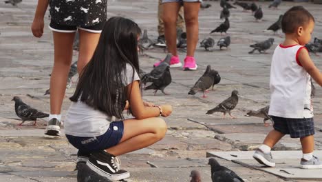 Young-Children-Being-Playful-Whilst-Feeding-Pigeons-In-Peru
