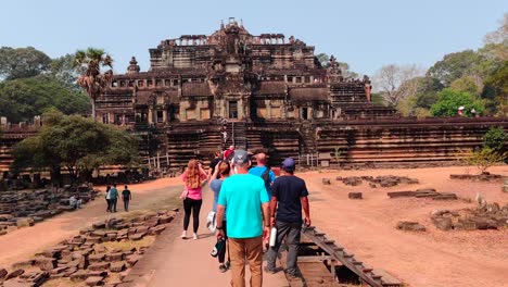 People-walking-towards-Ba-Phuon-Temple,-stopping-to-take-pictures-of-its-facade