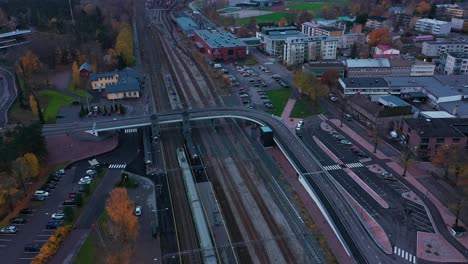 Aerial-view-of-a-train-arriving-at-a-railway-station,-rainy,-fall-day---orbit,-drone-shot