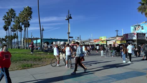 Menschen,-Die-Masken-Tragen,-Fahrrad-Fahren-Und-Sich-Während-Der-Covid-19-Krise-In-Los-Angeles,-Kalifornien,-USA,-An-Der-Strandpromenade-Von-Venice-Versammeln