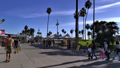 People-walking-around-the-Venice-Beach-Boardwalk-during-Covid-19-pandemic-shopping-and-enjoying-the-sunny-day-in-Los-Angeles,-Califonia,-USA