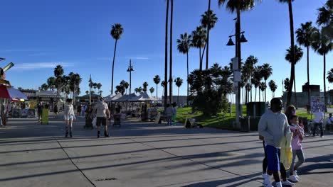 Menschen,-Die-Am-Venice-Beach-Boardwalk-Entlang-Des-Ocean-Front-Walk-In-Venedig,-Los-Angeles,-Kalifornien,-USA,-Spazieren-Gehen-Und-Inlineskaten-Fahren