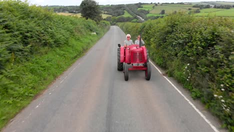 Vintage-Red-Tractor-Driving-Along-Country-Road
