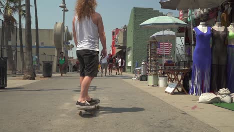 Cinematic-slow-motion-shot-of-Caucasian-male-on-skateboard-in-Venice-Beach,-CA