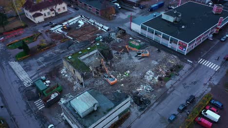Aerial-view-around-excavators-wrecking-a-urban-building,-gloomy-day---orbit,-drone-shot