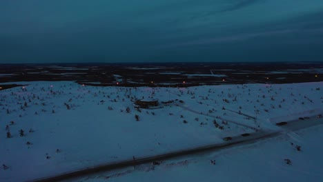 Aerial-drone-view-approaching-the-Tuikku-restaurant,-blue-hour-in-Levi,-Lapland