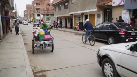 Male-Pushing-Metal-Street-Cart-Along-Road-In-Peru-Past-Traffic