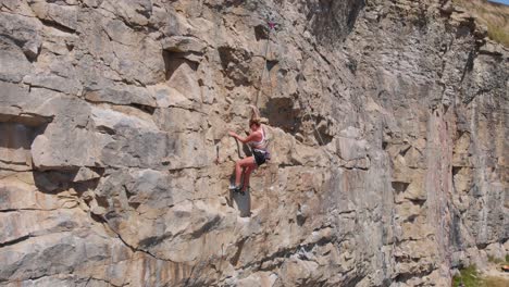 Aerial-Shot-Tracking-Female-Rock-Climber-at-Dancing-Ledge,-Jurassic-Coast,-UK