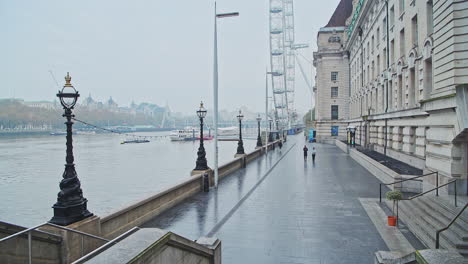 Quiet-and-empty-Central-London-at-the-London-Eye-during-Covid-19-Coronavirus-pandemic-lockdown,-with-two-people-running,-jogging-for-daily-exercise-in-the-city,-London,-England,-Europe