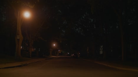 Dunkel-Beleuchtete,-Leere-Straße-In-Montreal,-An-Der-In-Der-Ferne-Ein-Auto-Vorbeifährt