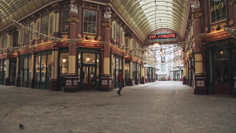 One-person-walking-in-an-empty-street-during-Coronavirus-Covid-19-lockdown-in-the-City-of-London-with-quiet-roads-and-shops-shut-during-the-global-pandemic-at-Leadenhall-Market-in-England,-Europe