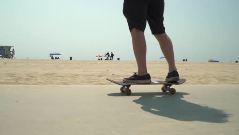 Cinematic-following-shot-of-Caucasian-male-on-skateboard-in-Venice-Beach,-CA