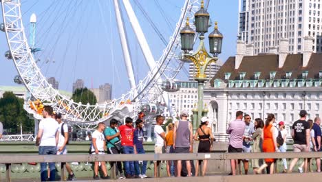 Statische-Aufnahme-Von-Touristen,-Die-Die-Westminster-Bridge-überqueren,-Mit-Dem-Millennium-Wheel-Des-London-Eye-Als-Hintergrund