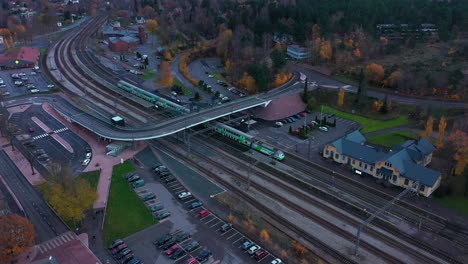 Aerial-view-of-a-VR-train-departure-at-a-city-station,-fall-day,-in-Finland---tilt,-drone-shot