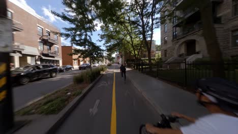 POV-En-Bicicleta-Detrás-De-Un-Hombre-Adulto-Vestido-Con-Ropa-Negra-A-Lo-Largo-De-Rachel-Street-En-Montreal