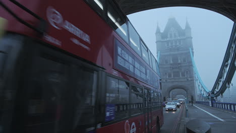 Red-London-Bus-driving-in-traffic-on-Tower-Bridge-in-London-in-foggy-misty-weather-on-a-cool-blue-morning-with-mist-and-fog-on-first-day-of-Coronavirus-Covid-19-Lockdown,-England,-Europe