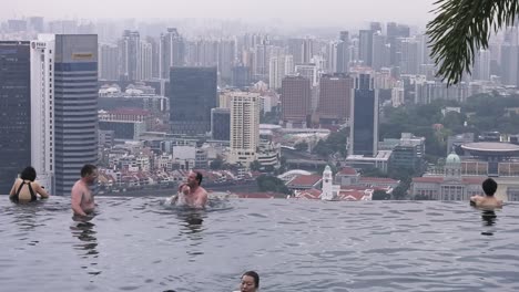 Tourist-Guests-relax-on-Infinity-Pool-at-the-famous-Marina-Bay-Sands-Hotel,-Singapore---Wide-static-shot