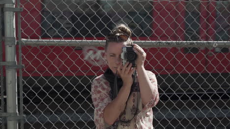 Female-photographer-taking-picture-while-train-passes-by-in-background