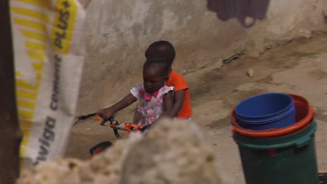 Zwei-Kleine-Kinder-Fahren-Mit-Dem-Fahrrad-Im-Hof-Hinter-Der-Wäscheleine-In-Sansibar