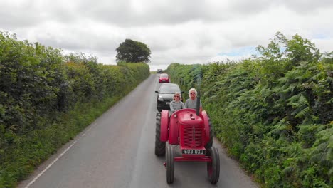 Old-Red-Tractor-Causes-Traffic-In-Country-Lane,-Devon,-UK