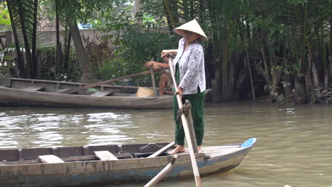 Vietnamesin-Mit-Einem-Traditionellen-Konischen-Blatthut,-Der-Ein-Boot-Im-Mekong-Flussdelta-Bewegt