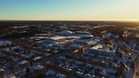 Aerial-view-of-the-Ouluhalli-sport-arena,-sunrise-in-Oulu---tracking,-drone-shot