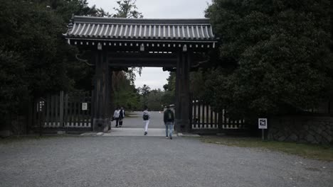 European-tourists-walking-into-the-imperial-palace-through-the-wooden-gates-in-Kyoto