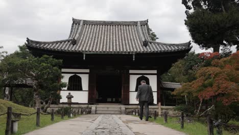 Japanese-guy-in-a-suite-walking-into-a-white-house-at-the-Kyoto-park