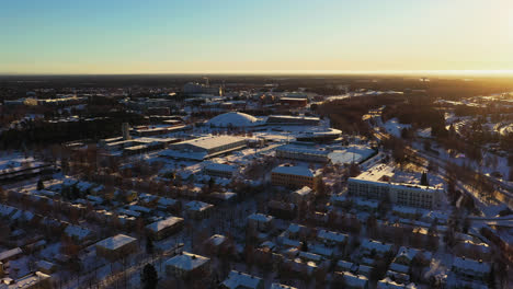 Aerial-drone-view-approaching-the-Ouluhalli-sport-arena,-winter-sunrise-in-Oulu