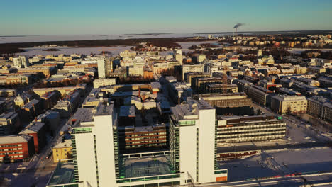 Aerial-view-of-the-downtown-Oulu,-winter-sunrise,-in-Finland---tracking,-drone-shot