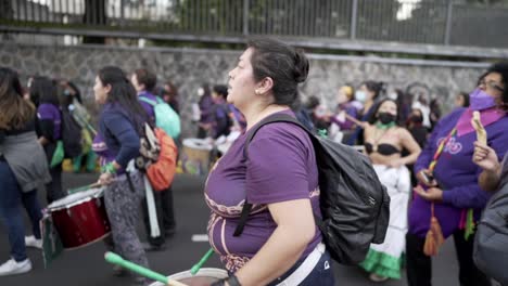 Una-Mujer-Con-Una-Camiseta-Morada-Toca-La-Batería-Con-Más-Mujeres-Durante-La-Protesta-En-El-Día-Internacional-De-La-Mujer-En-Quito,-Ecuador.