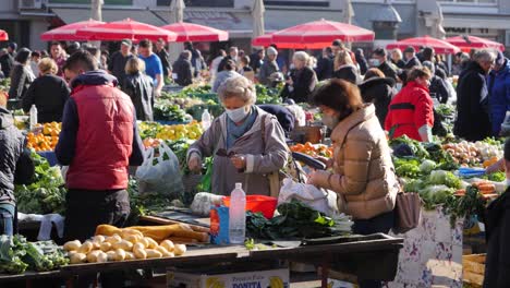 Woman-buy-vegetables-in-outdoor-market,-with-mask-at-the-end