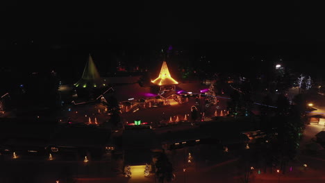 Nighttime-Aerial-View-of-Santa-Claus-Home-Town-Christmas-Lights,-Finland,-Tilt-Up-Shot
